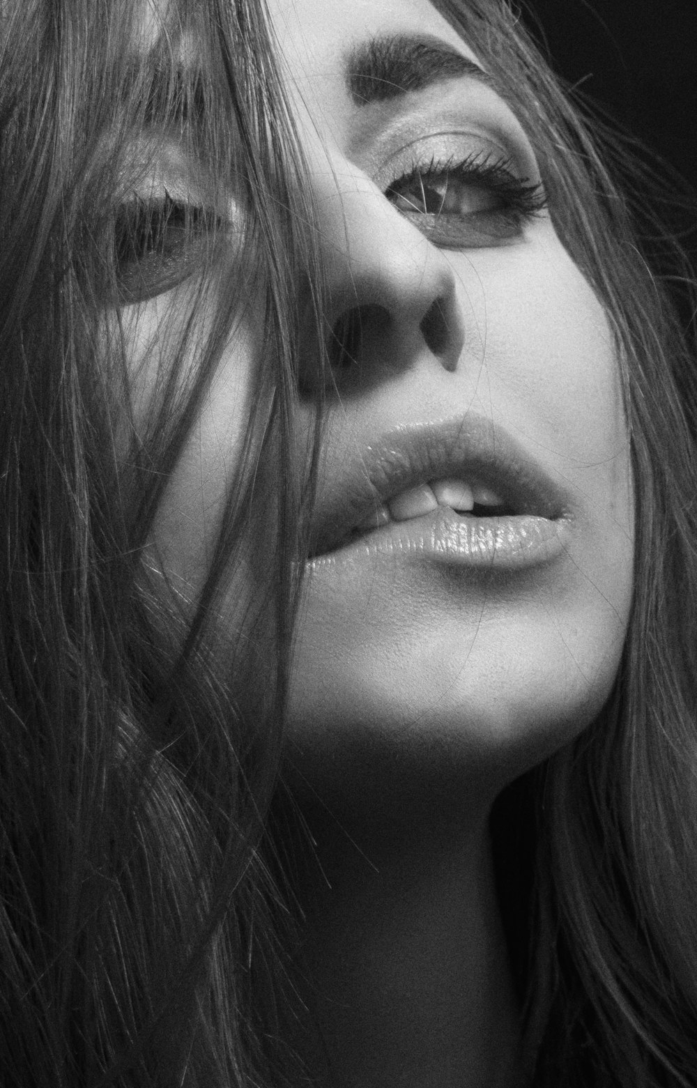 a black and white photo of a woman with her hair blowing in the wind