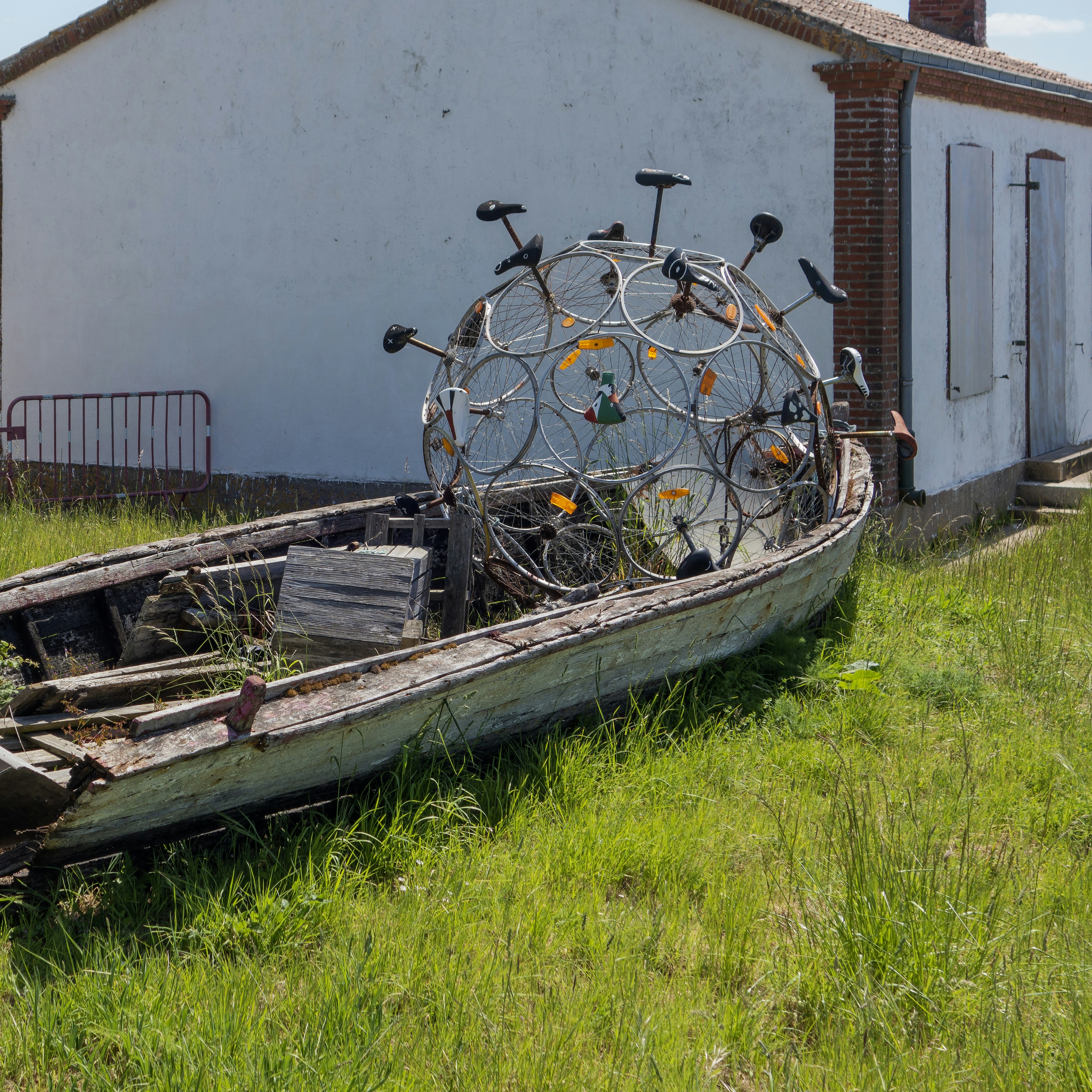 An old boat sitting in the grass next to a building photo – Free France ...