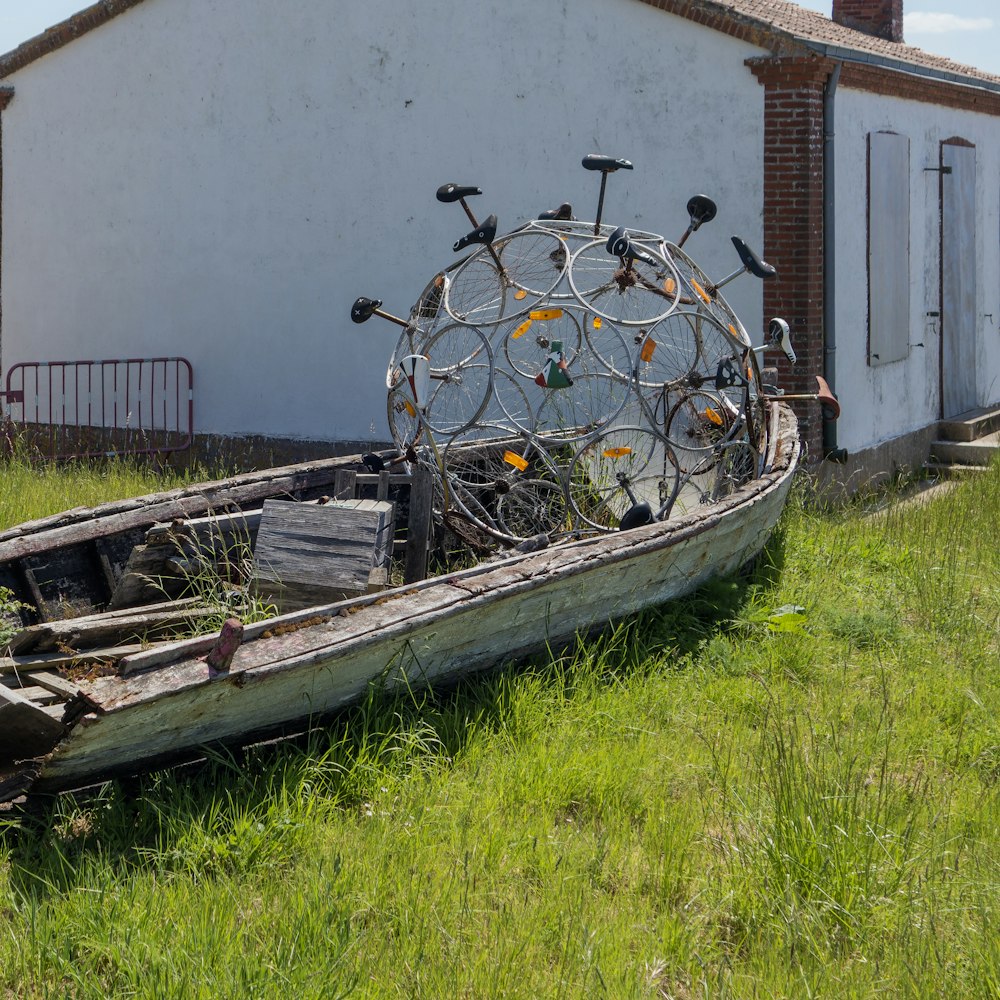 an old boat sitting in the grass next to a building