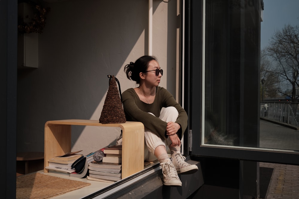 a woman sitting on a window sill looking out the window