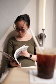 a woman reading a newspaper next to a cup of coffee
