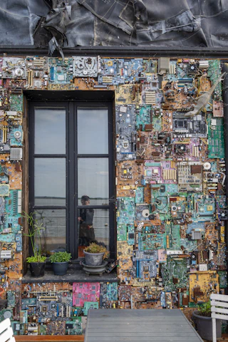 A cozy electronics workshop with soldering stations, circuit boards, and green plants symbolizing sustainability.