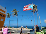 Bright graphic featuring the shield of a Puerto Rican town surrounded by palm leaves and seashells.