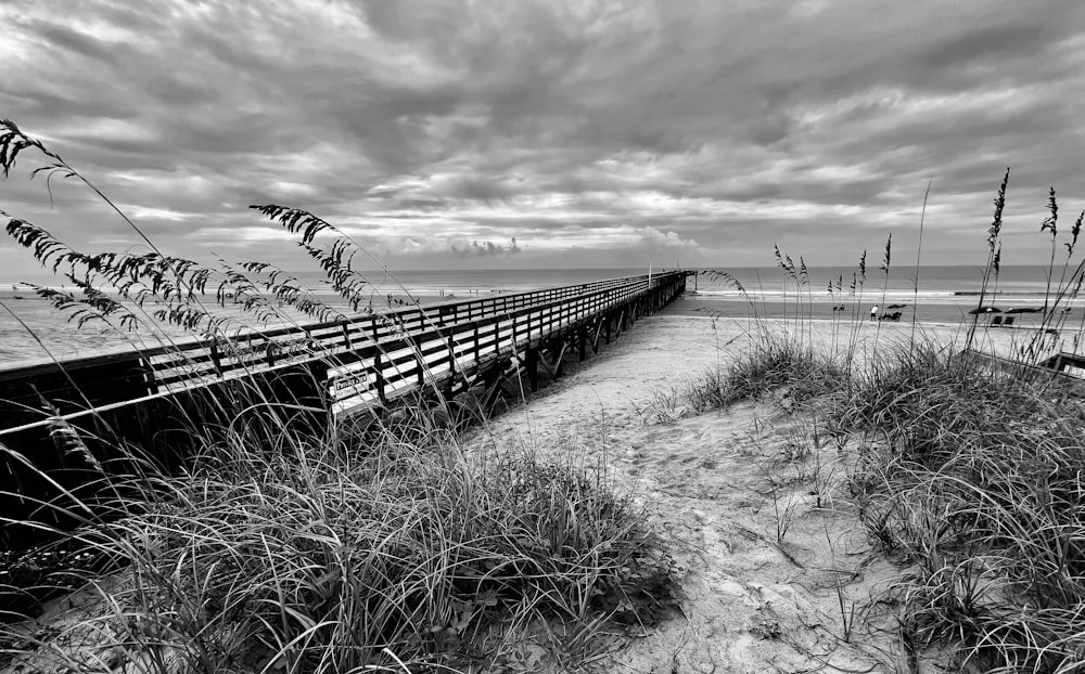 a black and white photo of a boardwalk and beach