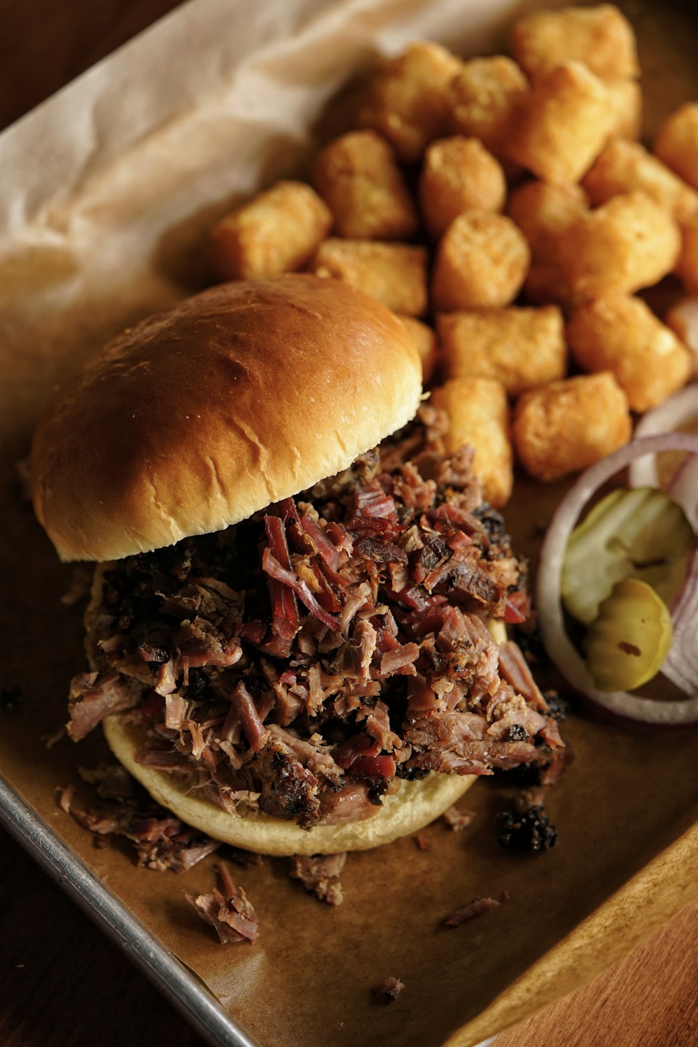 a pulled pork sandwich with a side of tater tots