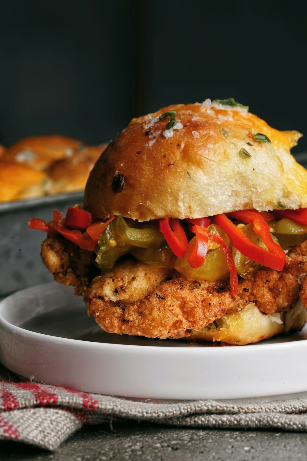 a fried chicken sandwich with peppers on a plate