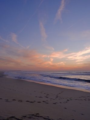 A tranquil beach at sunset with footprints in the sand.
