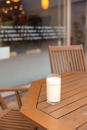 A chilled bottle of elhady llc beverage resting on a wooden picnic table with sunlight filtering through green leaves.