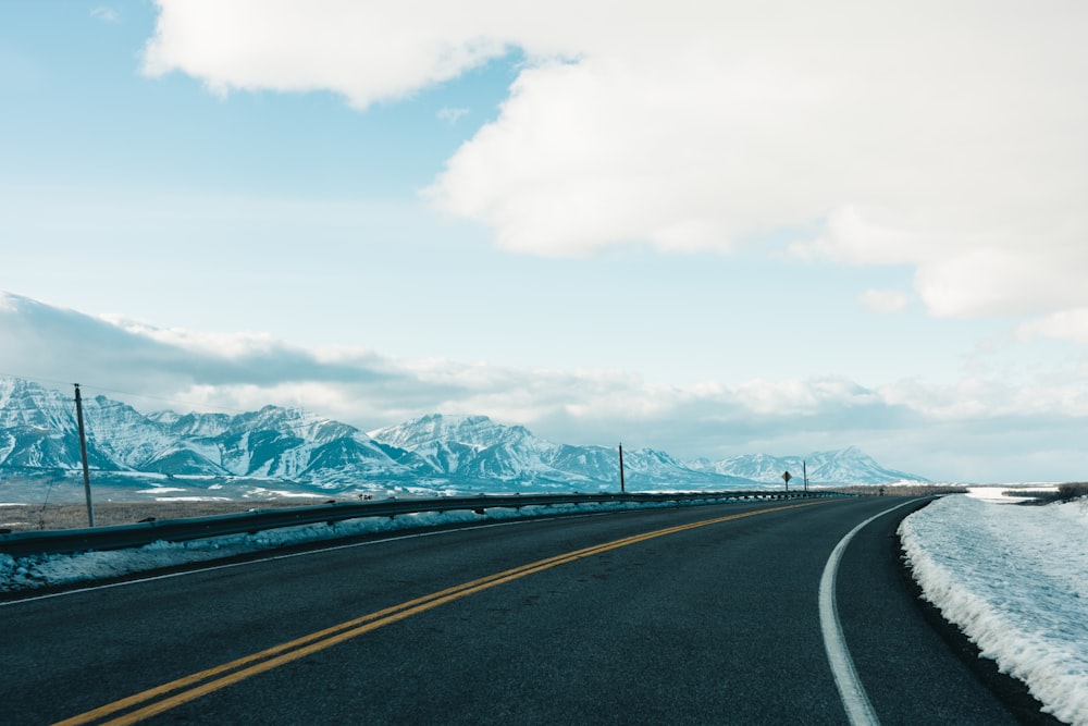 a road with snow and mountains in the background
