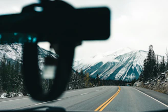 A scenic view of the Himalayas with a winding road and a comfortable car ready for a journey.