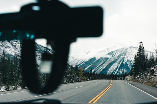 A scenic view of a car driving through the mountains.