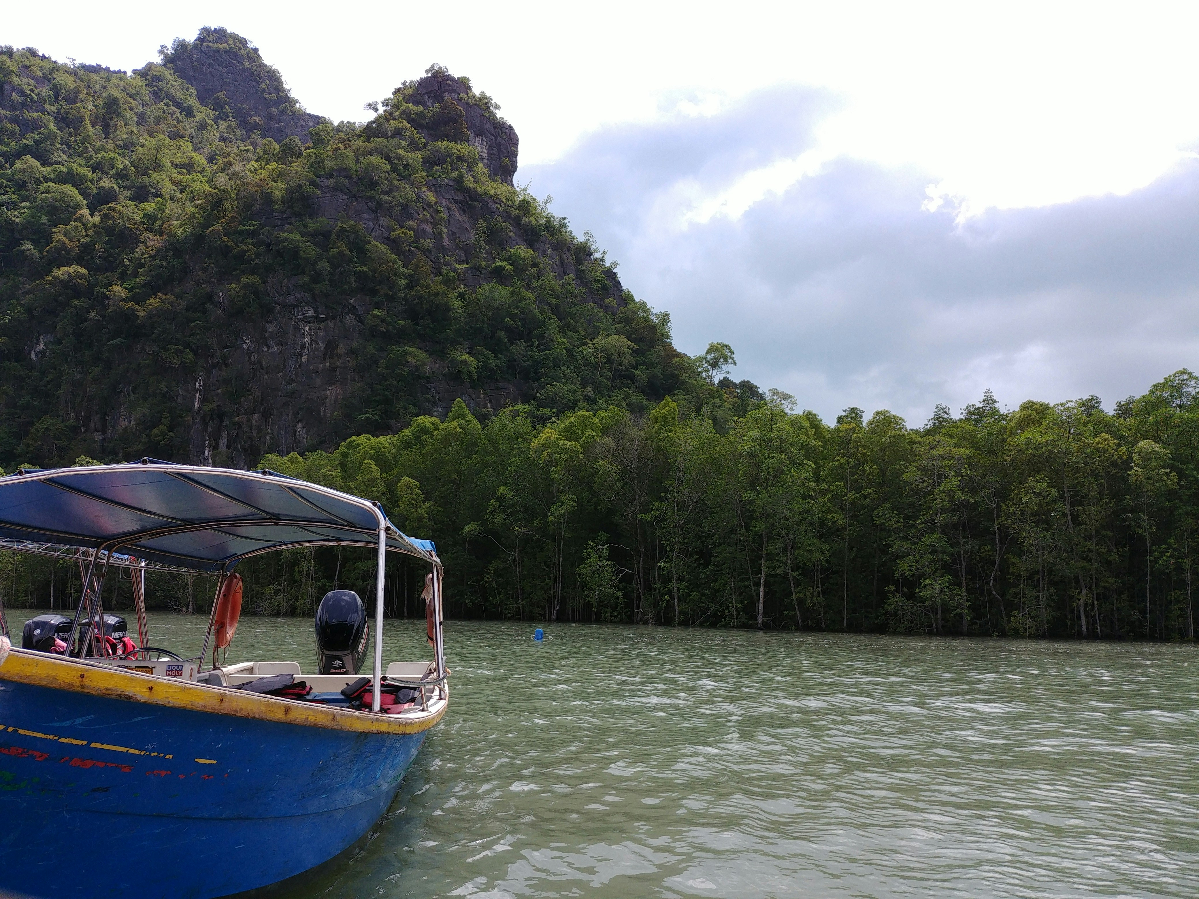 a blue boat floating on top of a lake next to a lush green forest