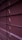 Horizontal window blinds are shown in a dimly lit setting with subtle gradients of purple and pink tones. Light peeks through the small openings between the slats.