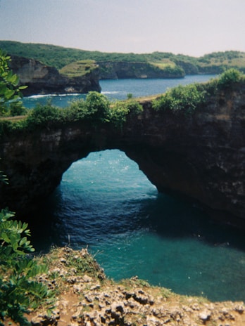 A picturesque shot of the iconic Broken Beach arch surrounded by lush greenery.
