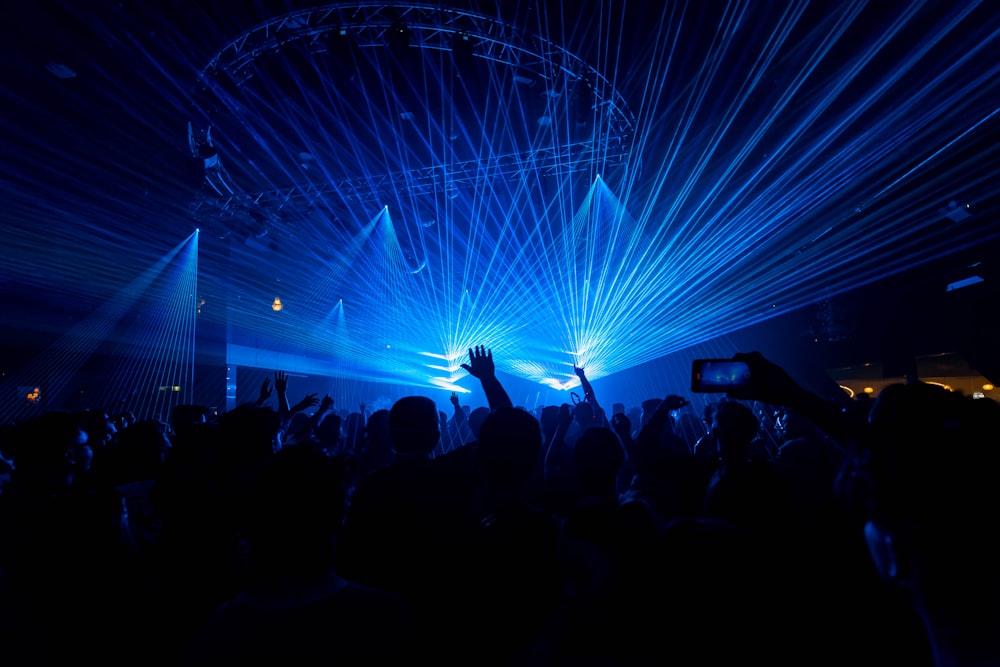 a crowd of people at a concert with their hands in the air