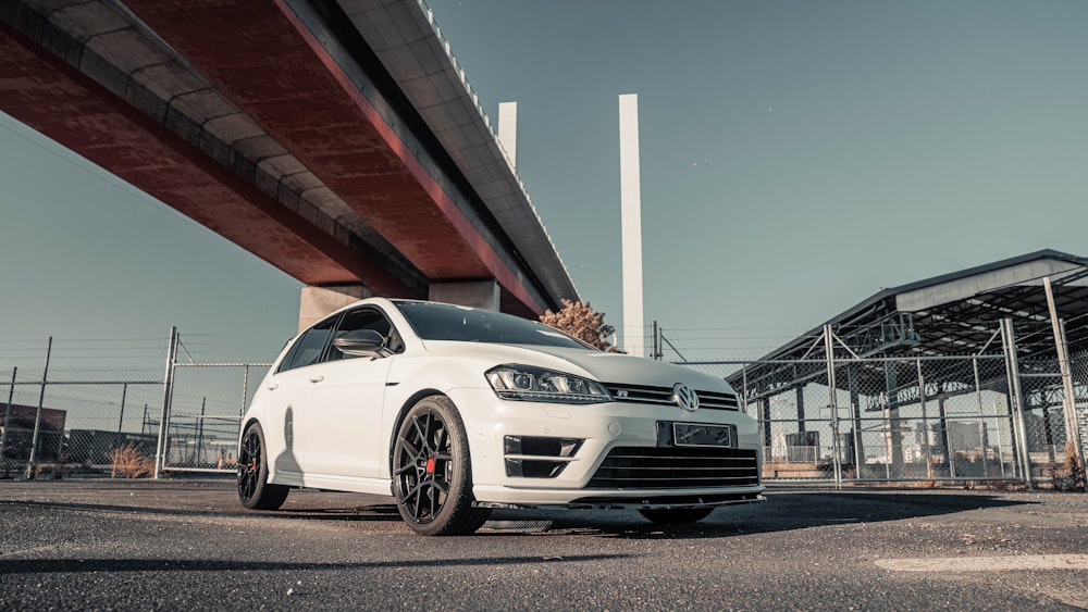 a white car is parked under a bridge