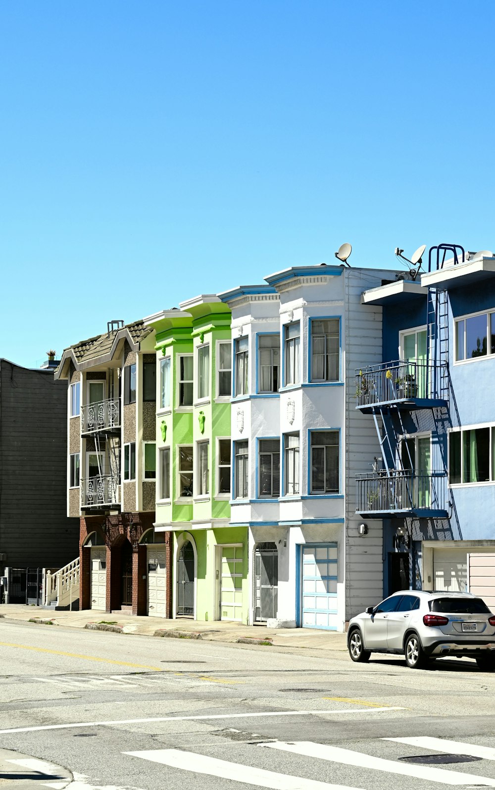 a row of multi - colored apartment buildings on a street corner