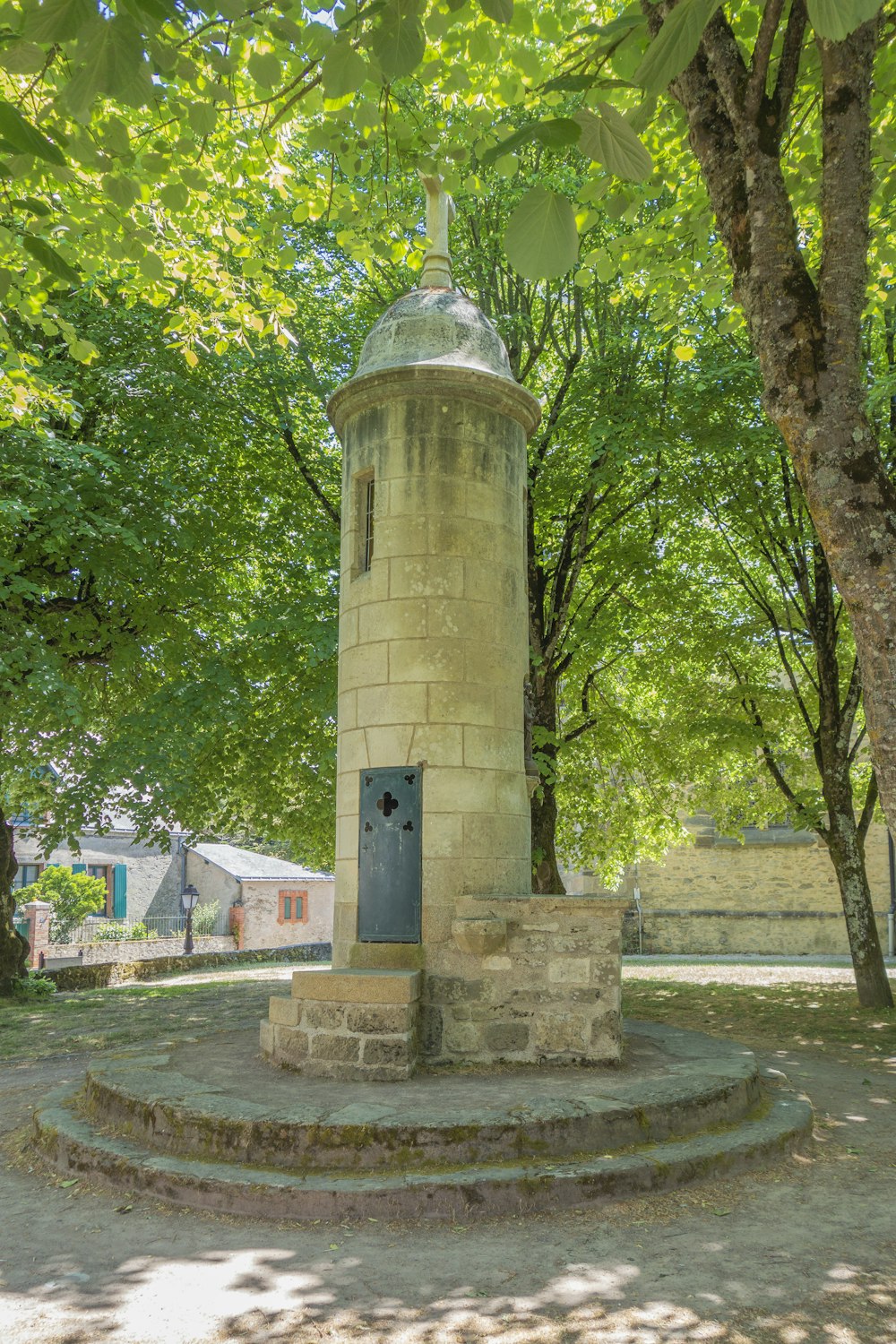 a stone tower in a park surrounded by trees