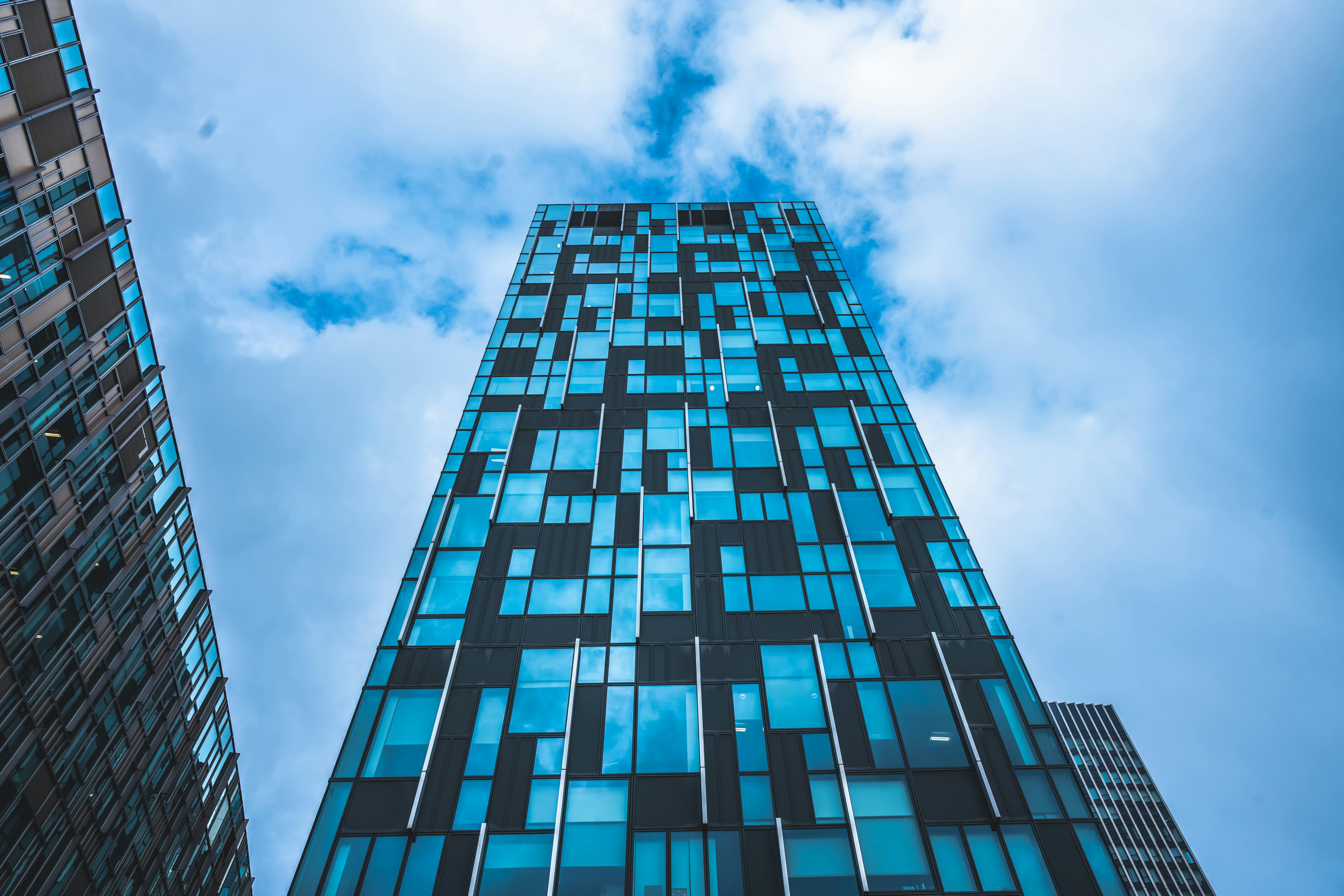 Modern glass and steel mixed-use tower building against blue sky in urban setting