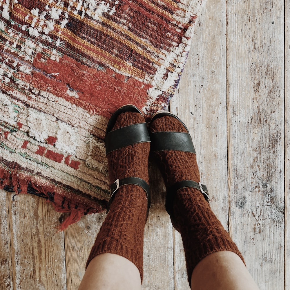 a person standing on a wooden floor next to a rug