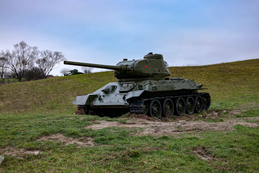 A sleek, high-tech military tank poised on rugged terrain under a stormy sky.