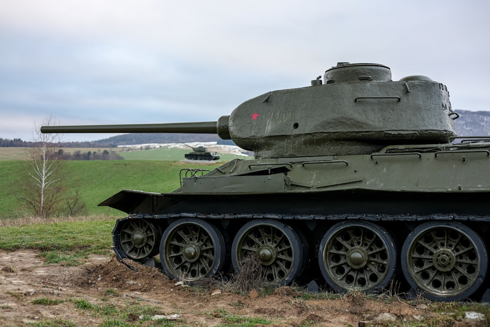 a tank is parked in a field near a hill