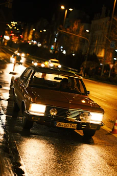 A comfortable VTC vehicle driving through the historic streets of Le Mans with city lights.