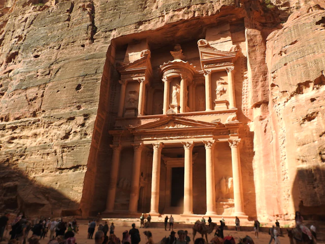 The Treasury's facade rising from the canyon floor with crowds of visitors gathered below
