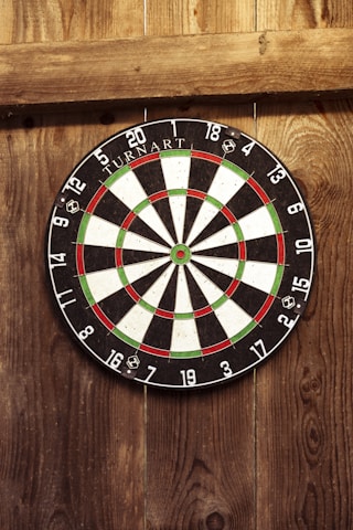 A vibrant dartboard setup in a cozy club environment with players engaged in a friendly game.