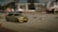 A gold BMW car is captured in mid-drift on an urban road, with blurred motion effects highlighting high speed. It is surrounded by a makeshift track marked by small barrels. Buildings and event tents are visible in the background, suggesting a motorsport event.
