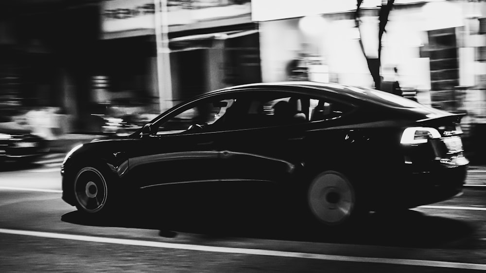 a black car driving down a street at night