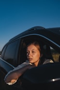 a woman sitting in a car looking out the window