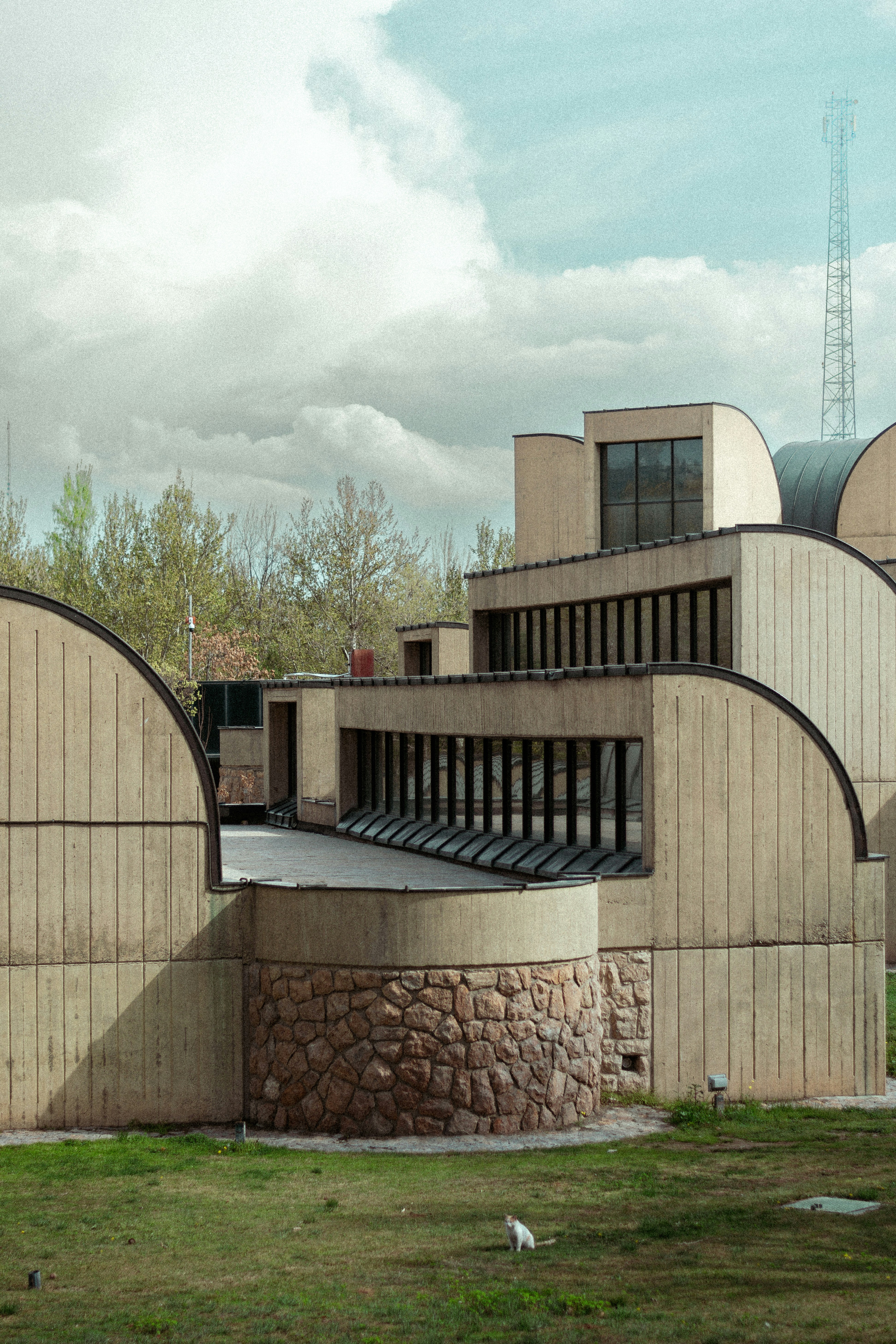 a building made of concrete with a clock tower in the background