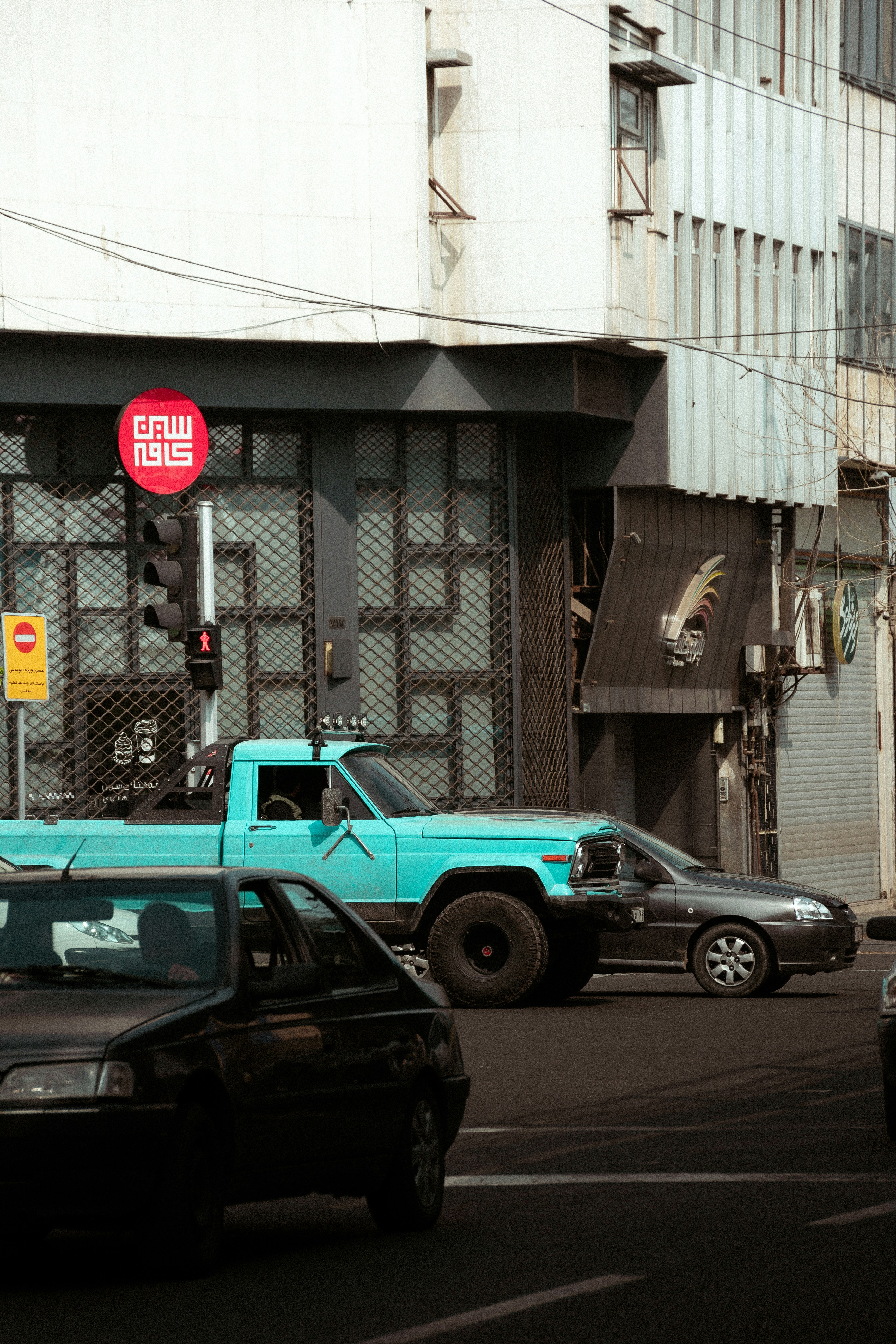 a blue truck driving down a street next to a tall building