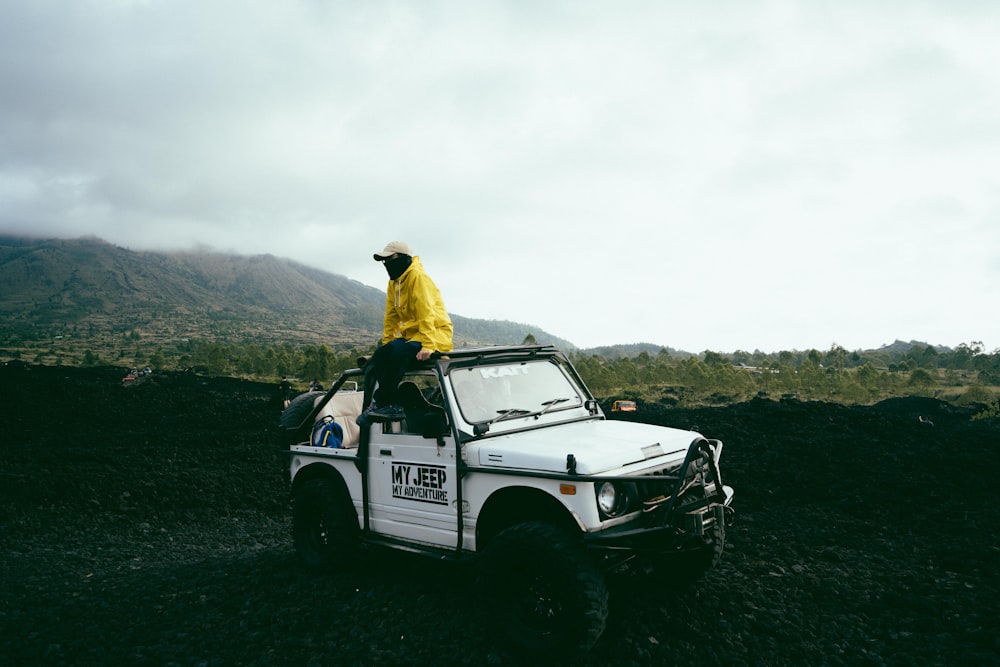 a man in a yellow jacket is sitting on top of a white truck