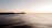A vibrant beach scene with surfers riding gentle waves at sunrise.