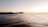 A vibrant beach scene with surfers riding gentle waves at sunrise.