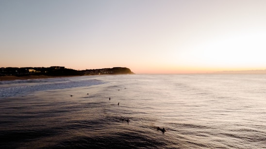 Sunset over surfers riding waves at a peaceful beach in León, Nicaragua