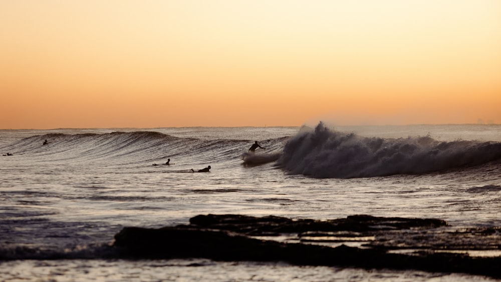 a group of surfers riding a wave in the ocean