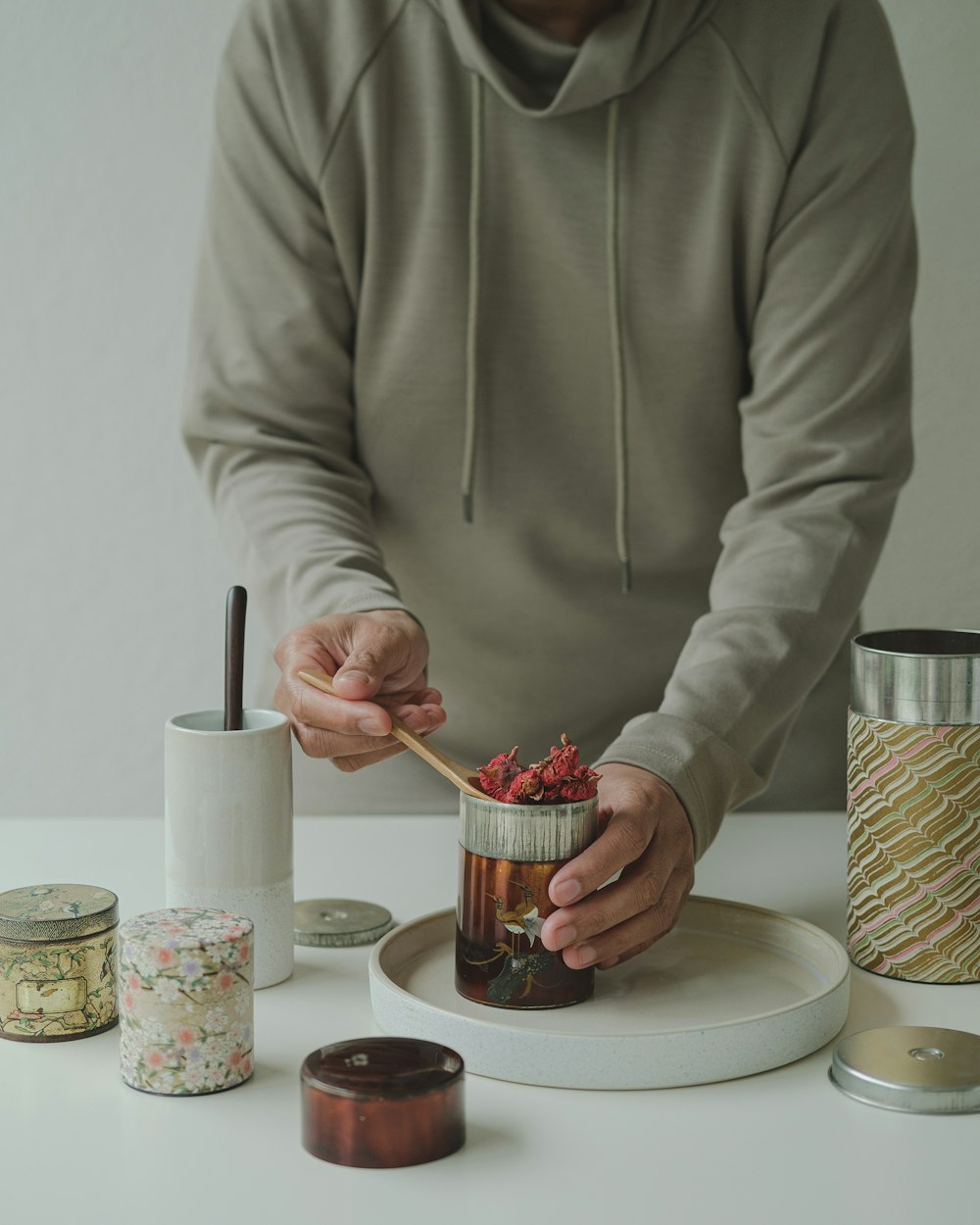 a person holding a spoon over a jar of food