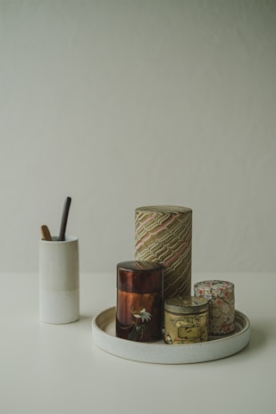 A set of enamel storage canisters neatly arranged on a kitchen shelf with woven jute table mats underneath.