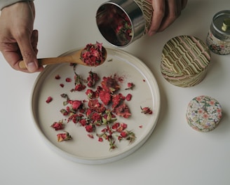 a person scooping rose petals out of a plate