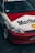 A customized car features a distinctive red and white paint job with large Marlboro and Shell logos. The car is equipped with aftermarket components, including sporty rims and a front bumper. The windshield displays a 'Streetweapon' decal, and there is evident branding inside the car on the seats.