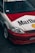 A customized car features a distinctive red and white paint job with large Marlboro and Shell logos. The car is equipped with aftermarket components, including sporty rims and a front bumper. The windshield displays a 'Streetweapon' decal, and there is evident branding inside the car on the seats.