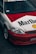 A customized car features a distinctive red and white paint job with large Marlboro and Shell logos. The car is equipped with aftermarket components, including sporty rims and a front bumper. The windshield displays a 'Streetweapon' decal, and there is evident branding inside the car on the seats.