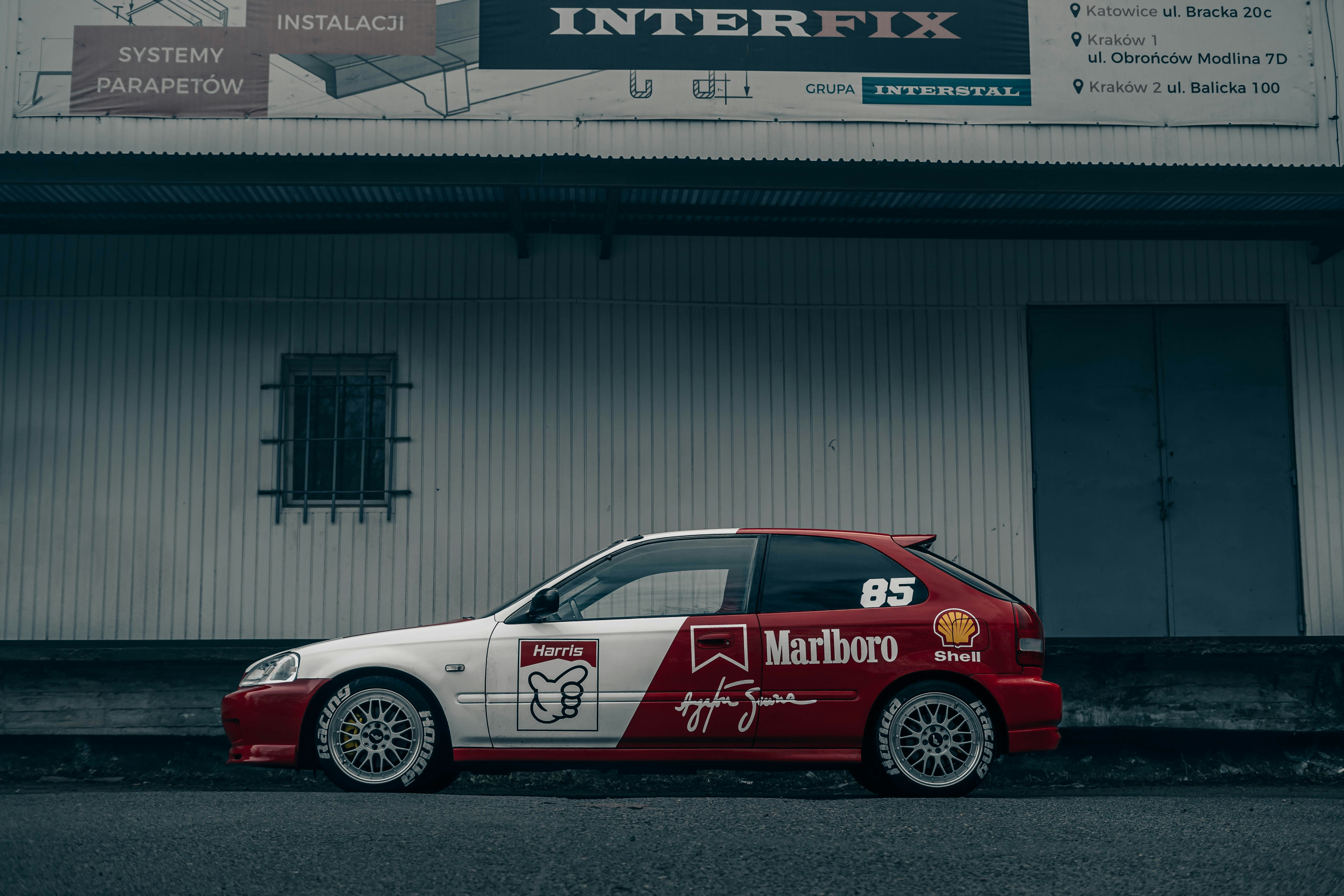 a red and white car parked in front of a building