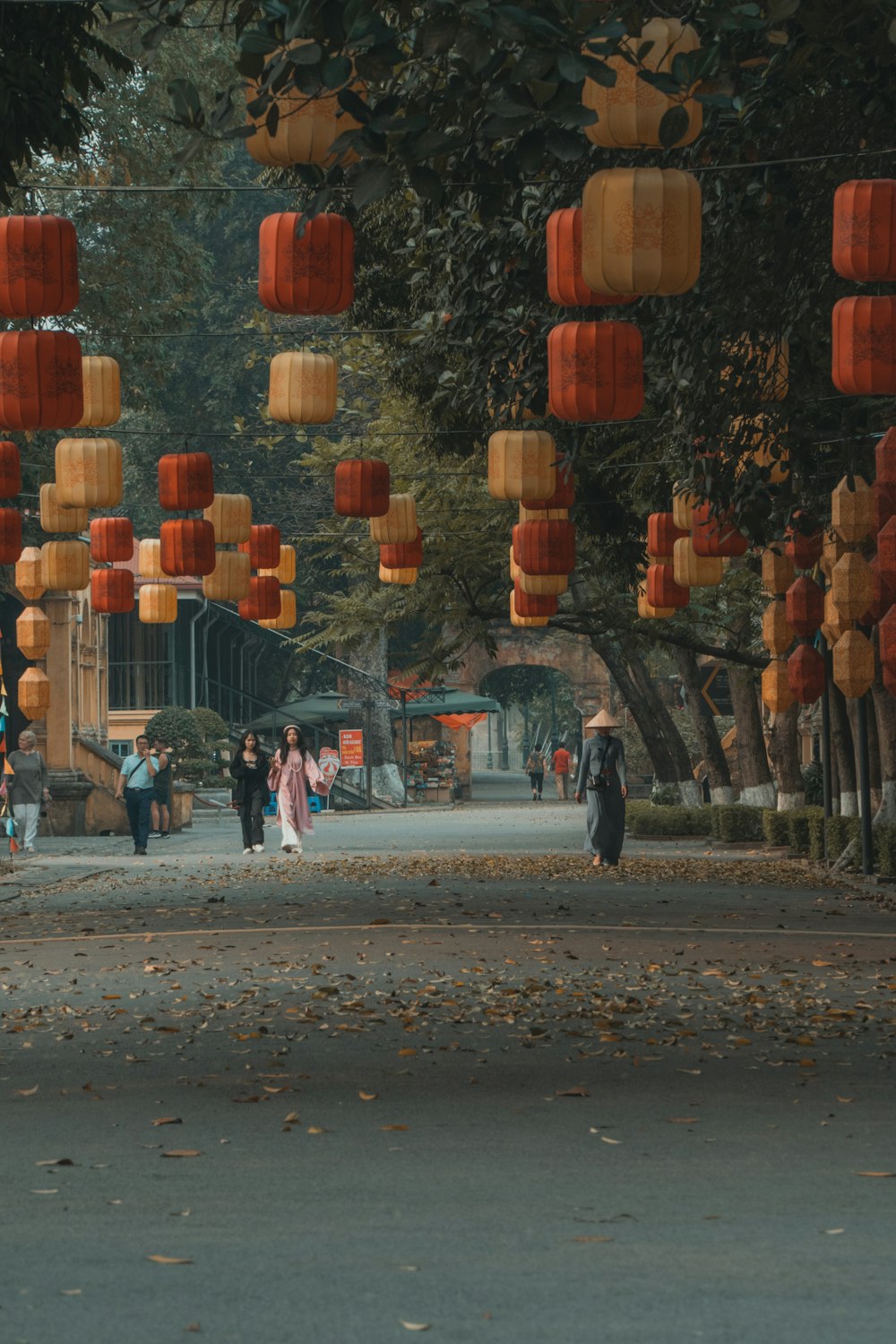 a group of people walking down a street under orange lanterns