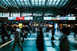 Nighttime shot of luminous LED advertising screens lighting up a railway station concourse filled with travelers.