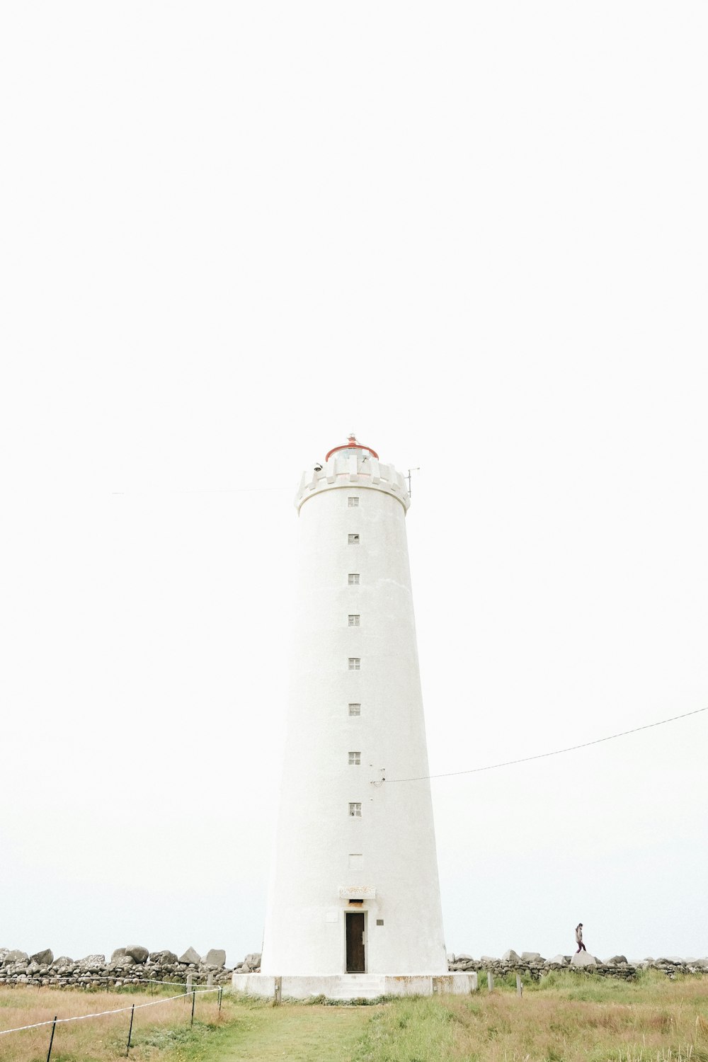 a white light house sitting on top of a lush green field