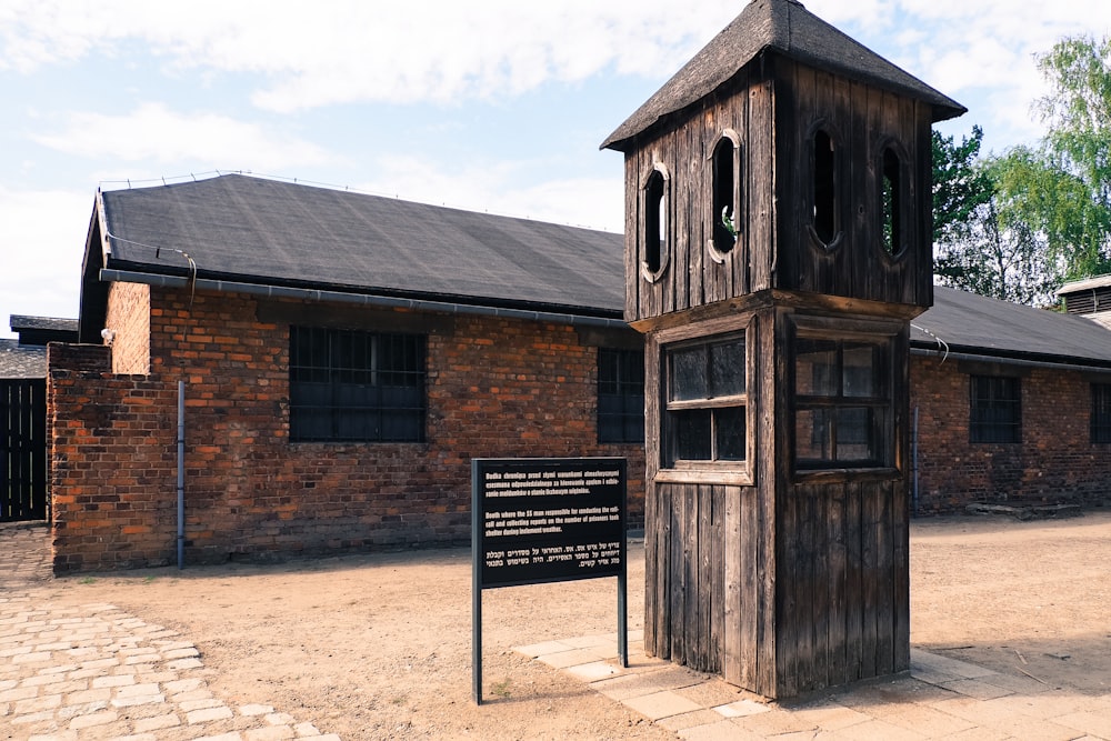 una alta torre de reloj de madera sentada junto a un edificio de ladrillo